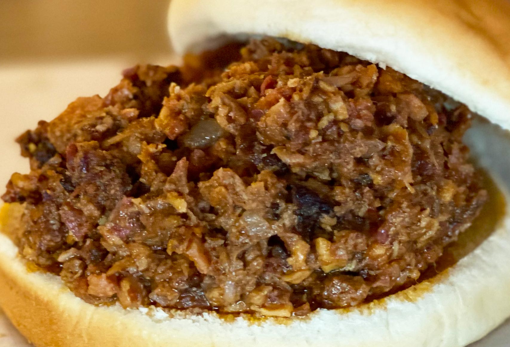 A closeup image of chopped BBQ on a bun